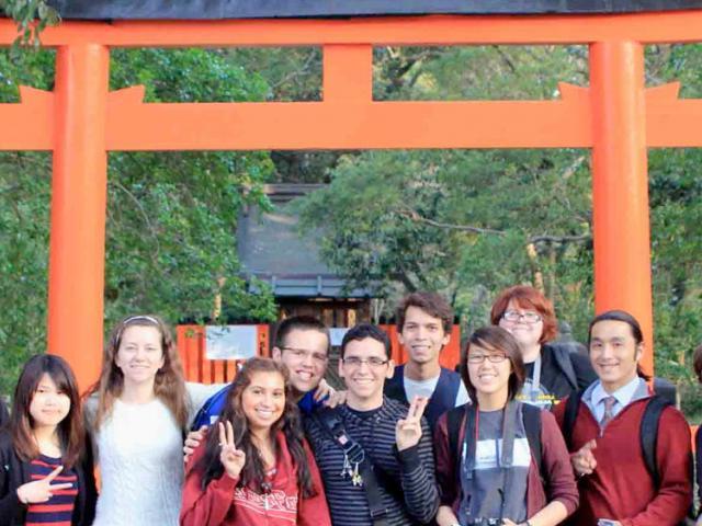 amjs澳金沙门 学生 pose in front of a shinto shrine in japan.